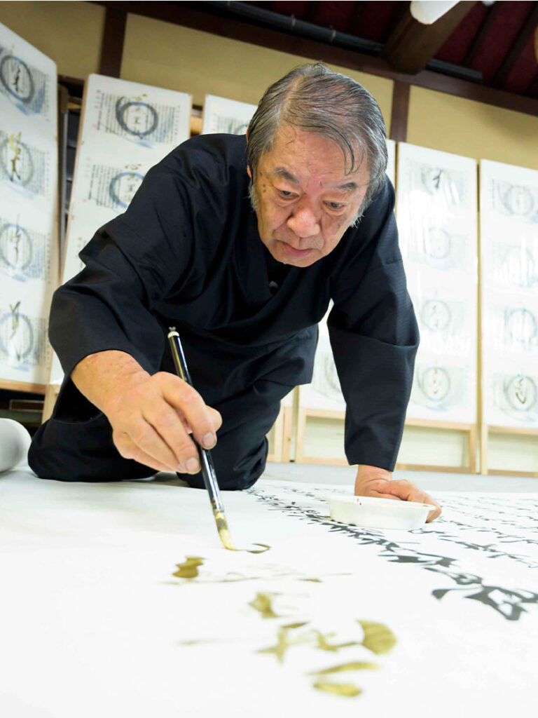 大きな紙に書を書く吉川壽一氏